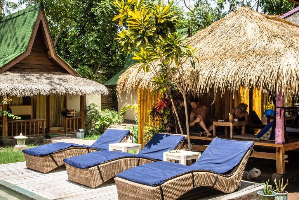 a group of chairs and umbrellas on a deck at H2O Peaceful Yoga Resort in Gili Air