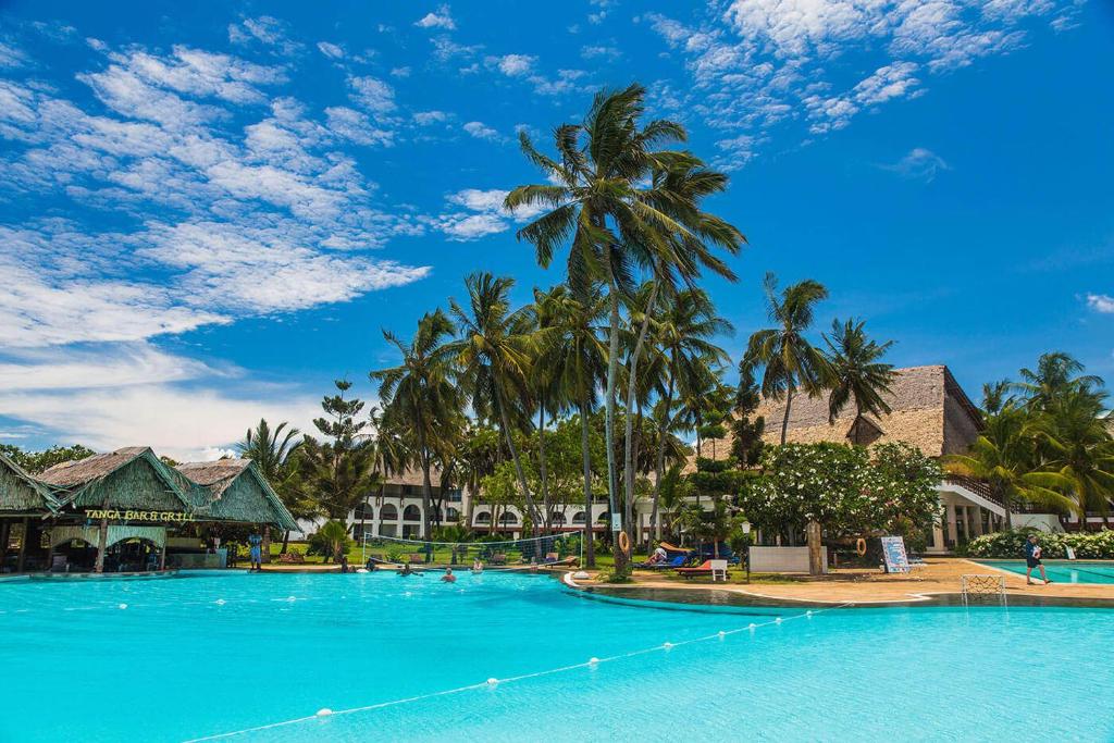 duży basen z palmami w ośrodku w obiekcie Reef Hotel Mombasa w mieście Mombasa