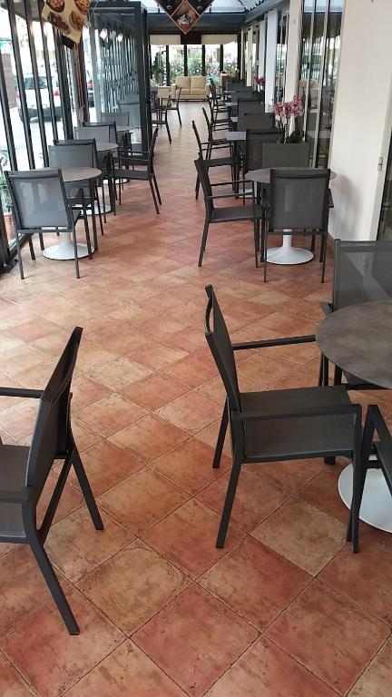 a room with tables and chairs on a tile floor at Hotel Venezia in Caorle