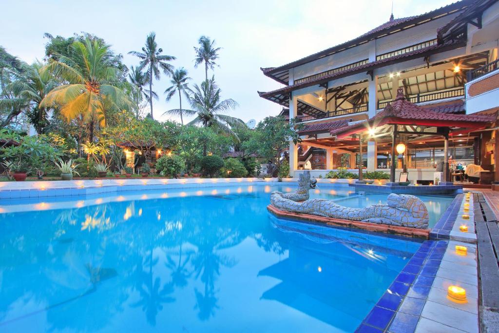 a swimming pool in front of a building at Puri Naga Beachfront Cottages in Legian