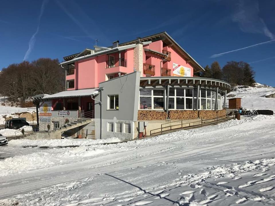 a pink building on top of a snow covered slope at Hotel Sole del Baldo in Brentonico