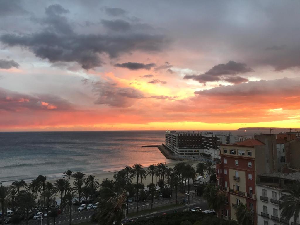 a sunset over the ocean with palm trees and buildings at Alicante loft in Alicante