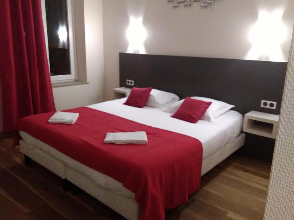 a bedroom with a large bed with red sheets and towels at Logis Le Provençal in Euville