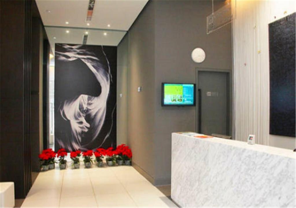 a lobby with red flowers and a large painting on the wall at Goldmet Inn Chengdu Baiguolin underground Station in Chengdu