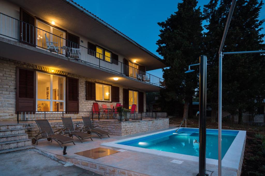 a swimming pool in front of a house at Villa Amalia in Murter