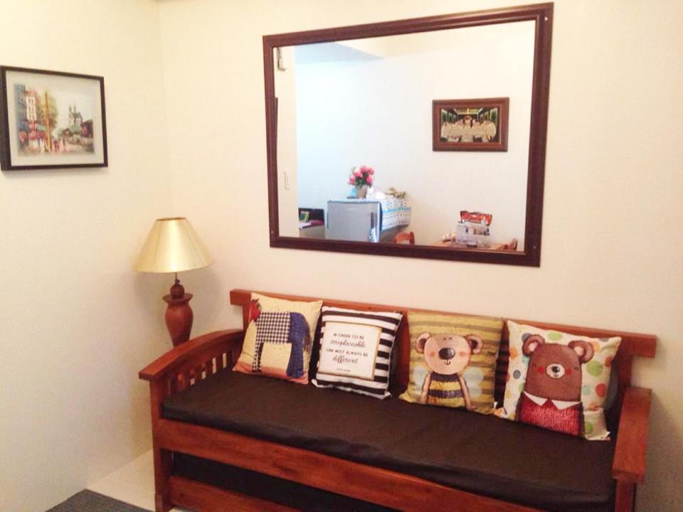 ein Spiegel über einer Bank mit Kissen darauf in der Unterkunft Hannah's Place at Wind Residences in Tagaytay