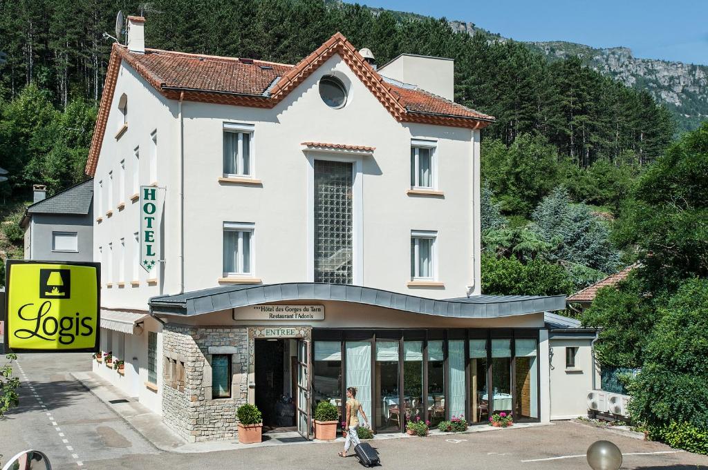 a woman walking in front of a building at Logis Hotel Restaurant des Gorges du Tarn in Florac Trois Riviere