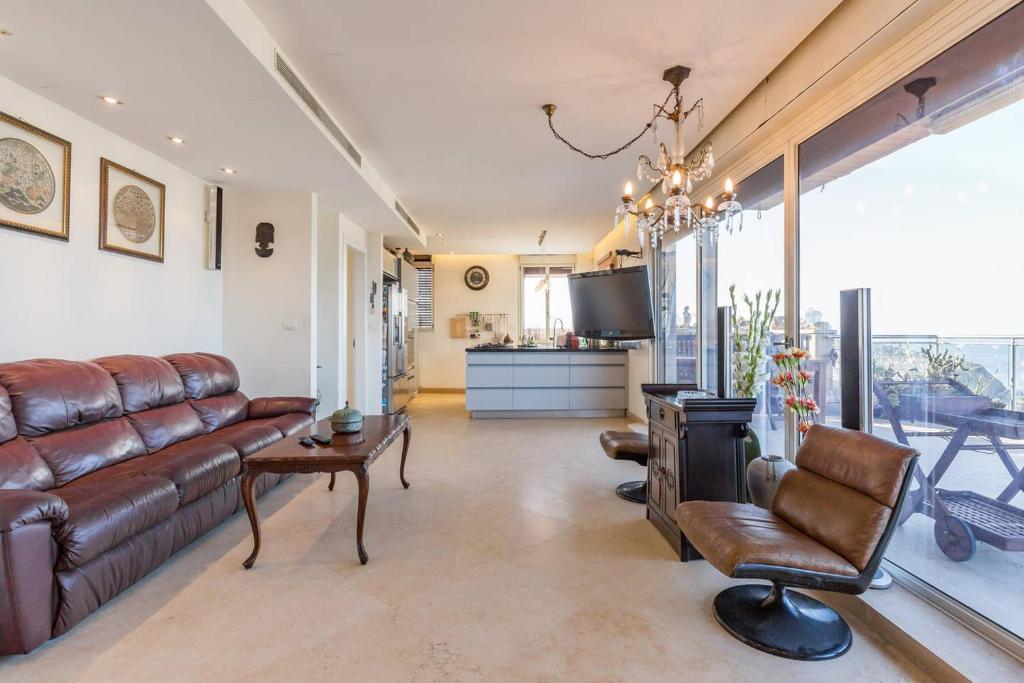 a living room with a leather couch and a tv at Jaffa Family Penthouse, sea front , 3BR, 2BA, in Tel Aviv
