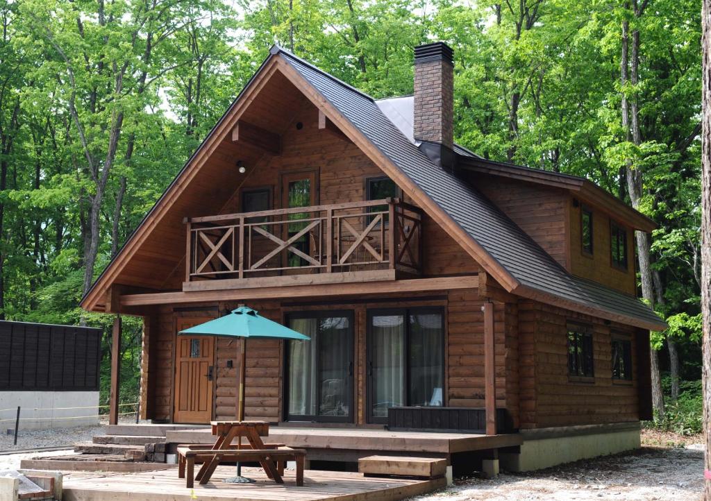 a log cabin with an umbrella in front of it at Log Cottage Epoch in Hakuba