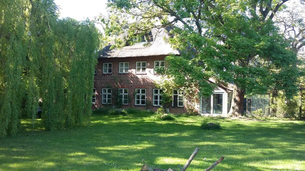 una antigua casa de ladrillo con un gran patio con árboles en Krüger-Hof Lübbersdorf, en Oldenburg in Holstein