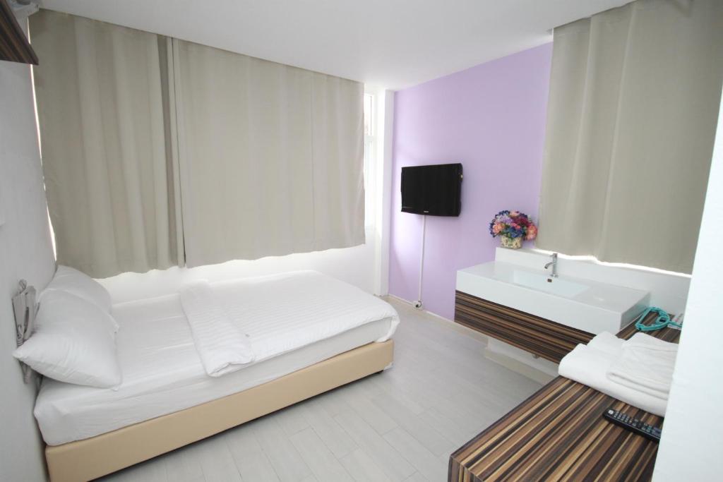 a small bedroom with a bed and a sink at Nantra Ekamai Hotel in Bangkok