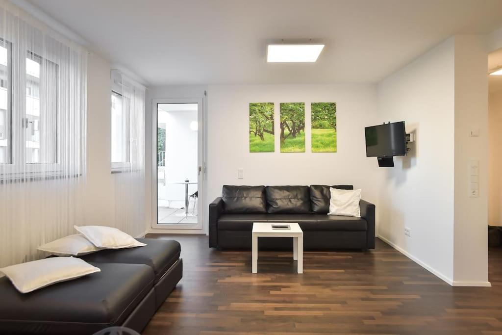 a living room with a black couch and a table at Deluxe Ferienwohnung Apartment Stuttgart Centre/Milaneo in Stuttgart