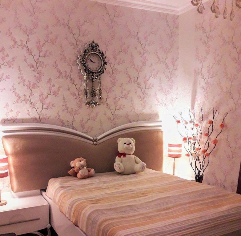 dos ositos de peluche sentados en una cama en un dormitorio en apartamenti drevni batumi, en Batumi