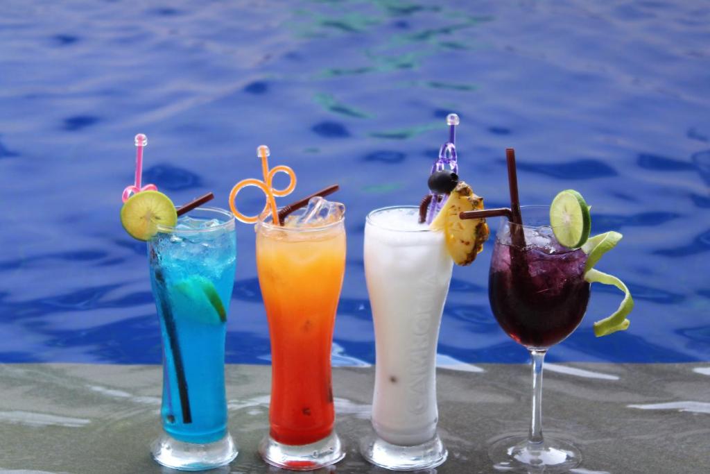 three cocktails sitting on a table next to a pool at Siem Reap Pub Hostel in Siem Reap
