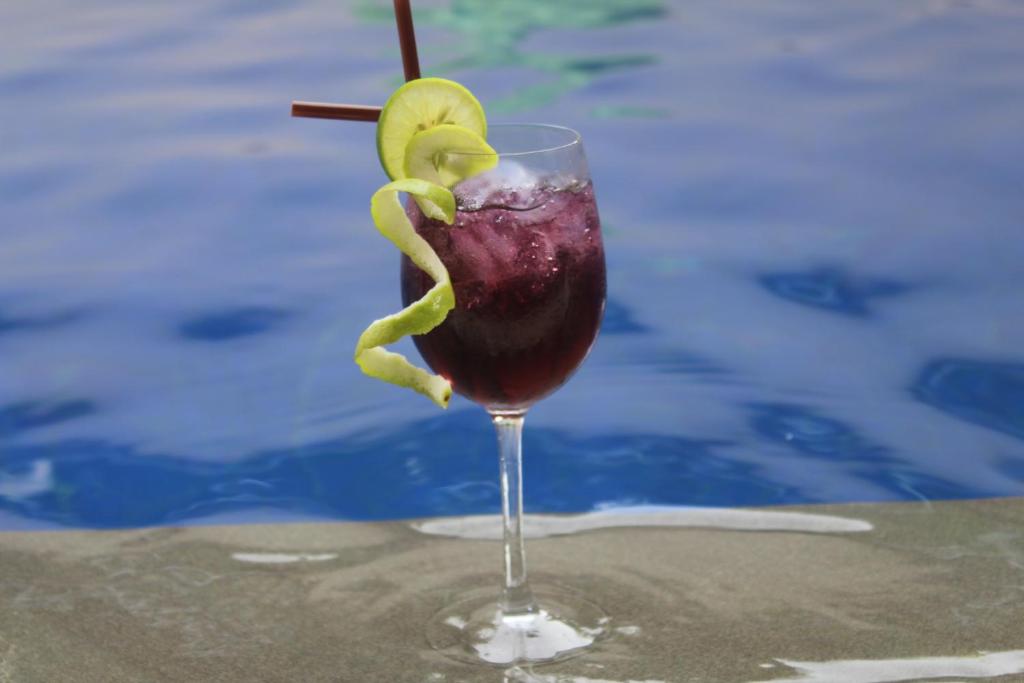 a drink in a glass sitting next to a pool at Siem Reap Pub Hostel in Siem Reap