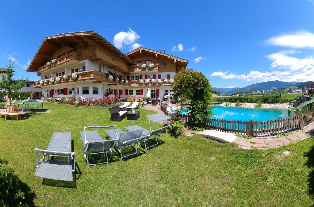 une grande maison avec des chaises et une piscine dans l'établissement Aparthotel Dachsteinblick, à Flachau