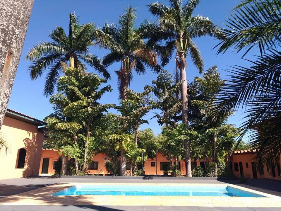 a swimming pool in front of a house with palm trees at Vitalliti Hotel in Alta Floresta