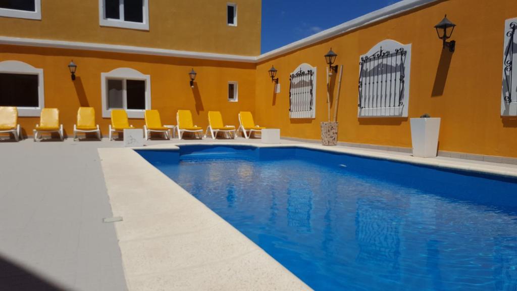 a swimming pool in a building with yellow walls and yellow chairs at Hotel Colonos in Las Grutas