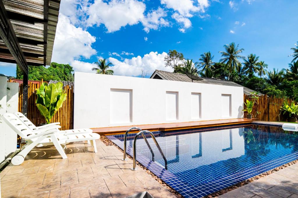 a swimming pool with two white chairs next to a house at S2 Residence in Ao Nang Beach