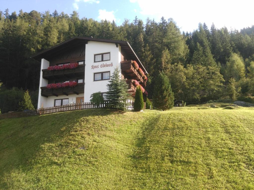 un edificio en una colina con un campo de césped en Haus Edelweiß, en Jerzens