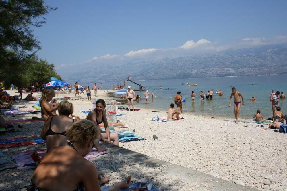 a group of people sitting on a beach at Camping Planik in Ražanac