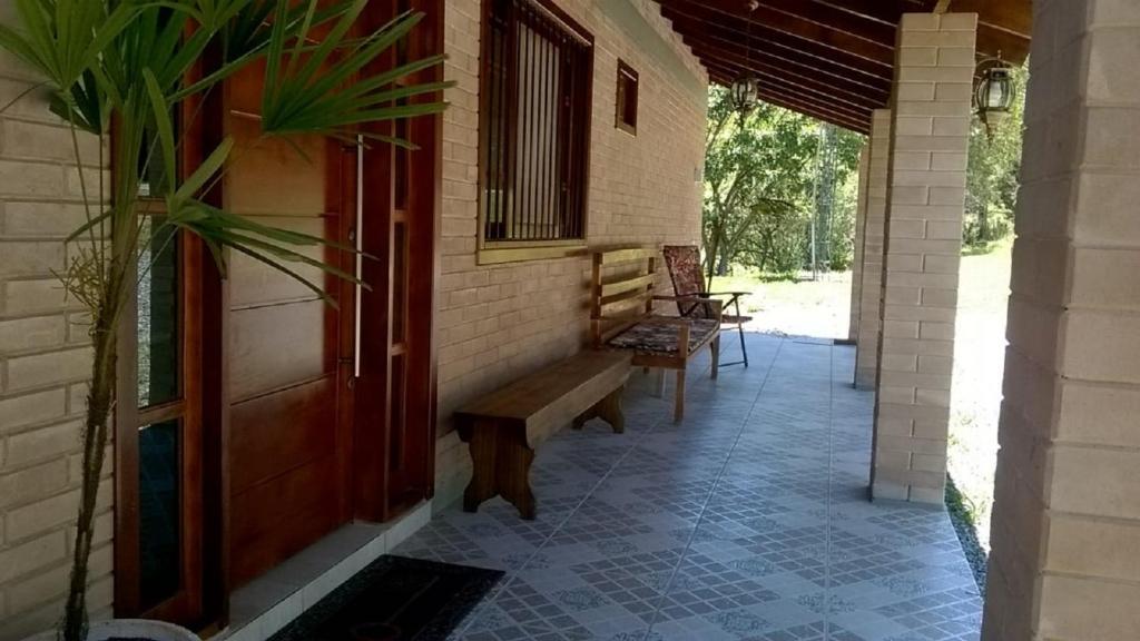a porch of a house with a bench and a door at Pousada Punta Cana in Estância Teixeira