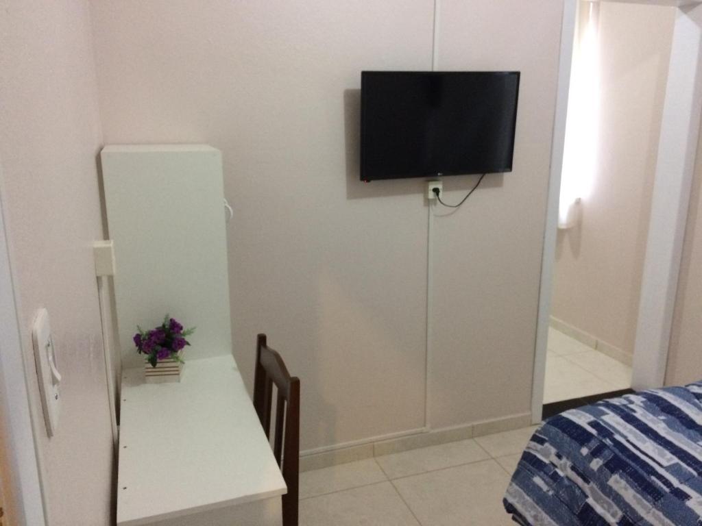 a room with a television on a white wall with a bed at Hotel Ferrari in Rio do Sul