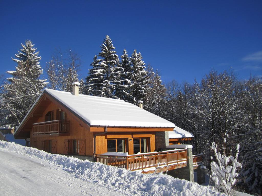 a log cabin in the snow with snow covered trees at Chalet Les Jumelles in Les Allues