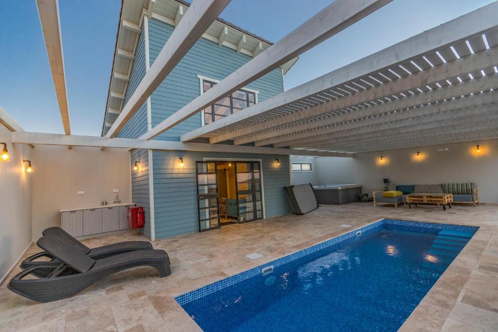 an indoor swimming pool in a house with a large ceiling at Gold 68 in Kefar Barukh