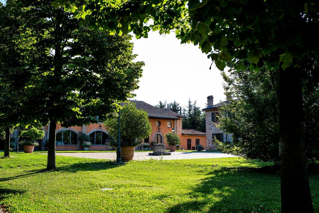 una casa con un patio con césped verde y árboles en Relais Cascina Scottina en Cadeo