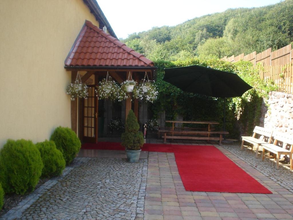 un patio con alfombra roja y sombrilla en Zielone Wzgórze, en Wałbrzych