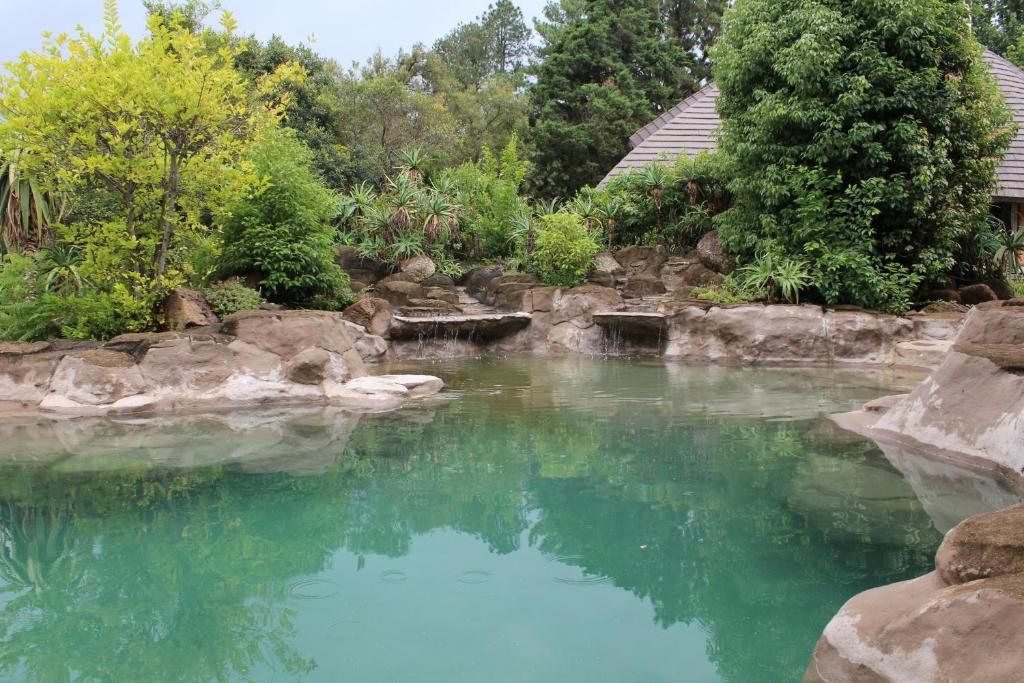 una piscina de agua azul con rocas y árboles en Treks, Trips and Trails, en Champagne Valley