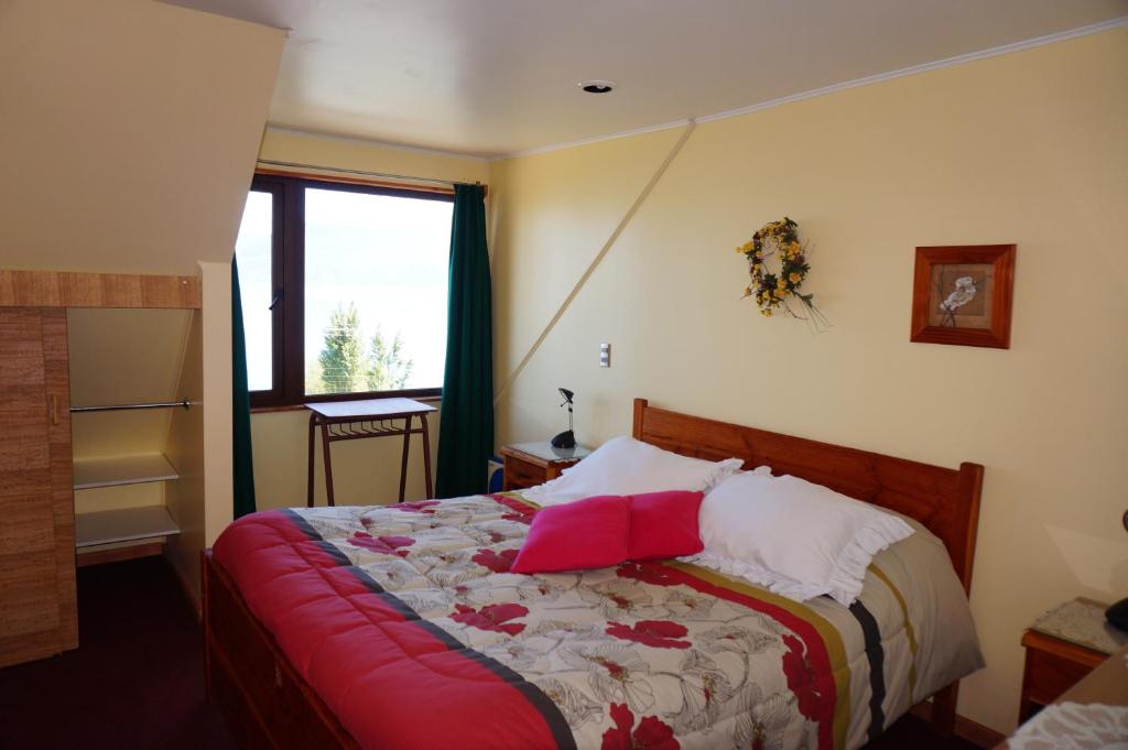 Un dormitorio con una cama con almohadas rojas. en Los Gualles de la Candelaria Apart Hotel en Pucón