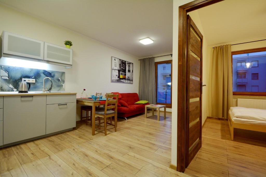 a kitchen and living room with a red couch and a table at Apartament Bema 37 in Wrocław