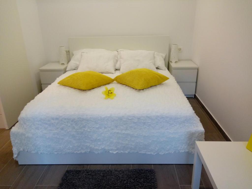 Una cama con dos almohadas y una flor amarilla. en Apartma Neža, en Bled