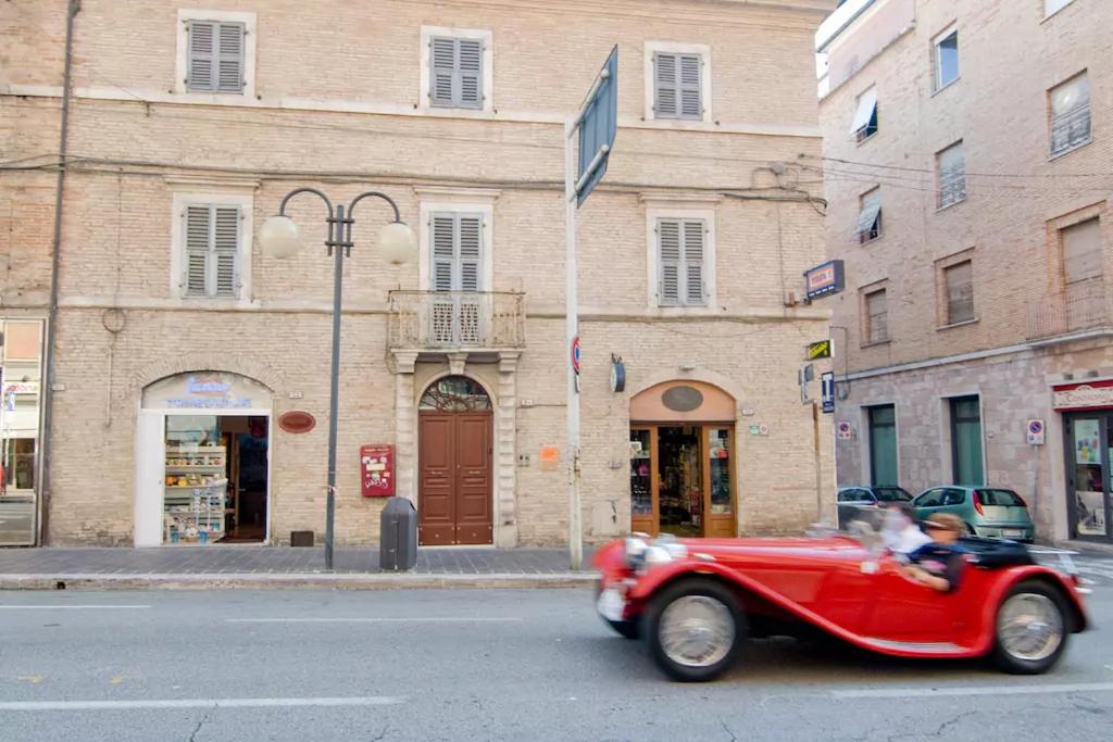 un coche rojo conduciendo por una calle frente a un edificio en La casa di Oliva, en Macerata