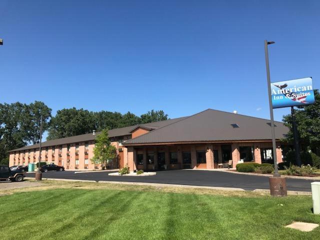 a large building with a sign in front of it at American Inn and Suites Ionia in Ionia