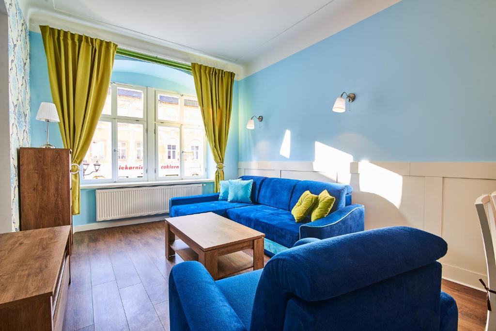 a blue living room with two blue couches and a table at Apartament Kowary - Na Kowarskiej Starówce II in Kowary