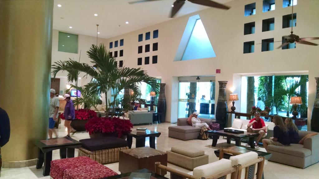 a lobby with people sitting on couches in a building at Suites at Mayan Palace Vidanta Resort Riviera Maya in Playa del Carmen