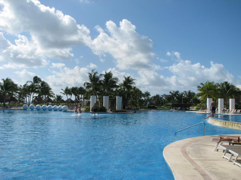 a large swimming pool with palm trees in the background at Suites at Mayan Palace Vidanta Resort Riviera Maya in Playa del Carmen