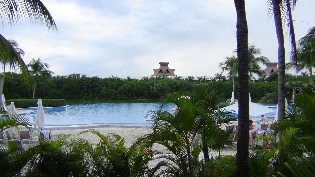 a view of a pool at a resort with palm trees at Suites at Mayan Palace Vidanta Resort Riviera Maya in Playa del Carmen