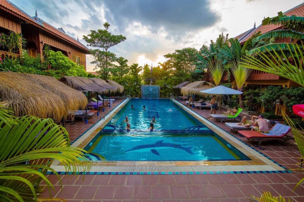 a pool at a resort with people swimming in it at Delux Villa in Battambang