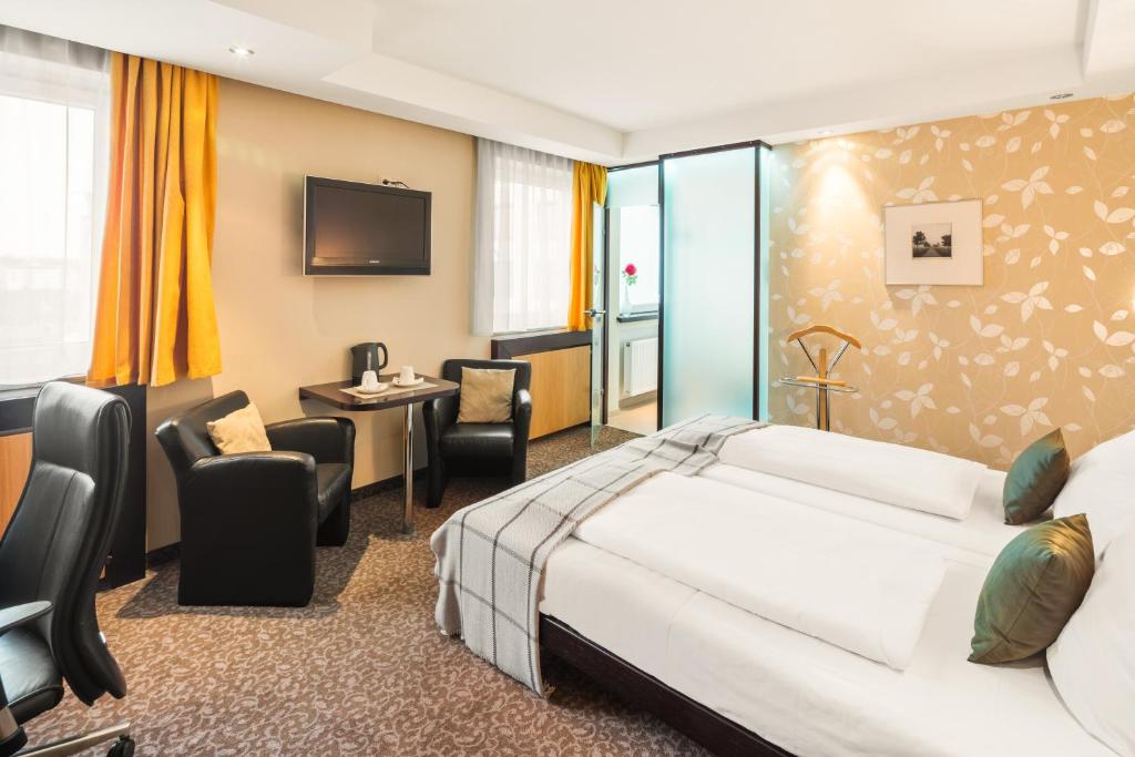 ein Hotelzimmer mit einem Bett und einem Schreibtisch in der Unterkunft L'Escala in Dreieich