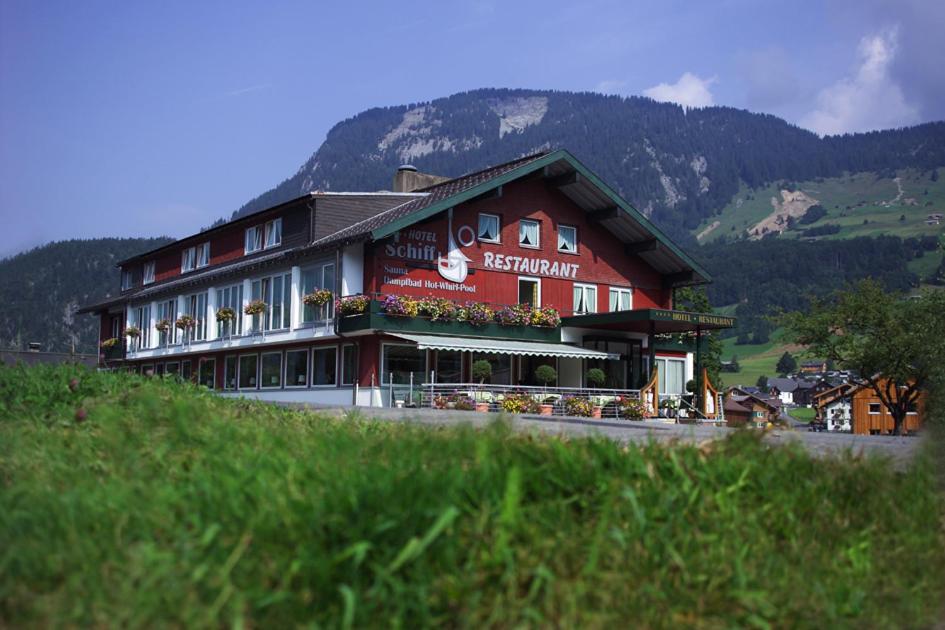 ein großes rotes Gebäude mit Blumen davor in der Unterkunft Das Schiff in den Bergen in Au im Bregenzerwald