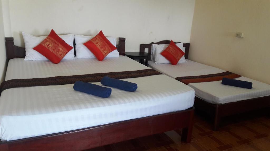 two beds in a room with blue and red pillows at Bang Son Golden View in Baan Khai