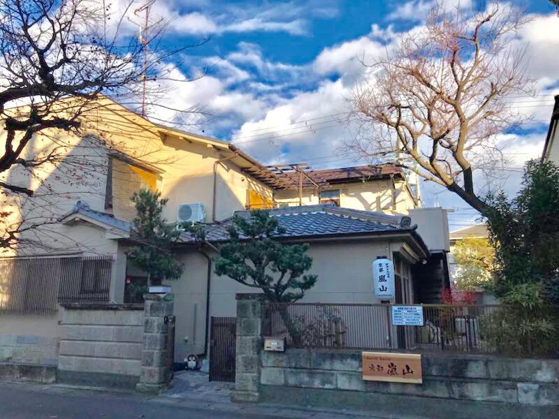 uma casa branca com uma cerca à frente. em Guesthouse Kyoto Arashiyama em Quioto