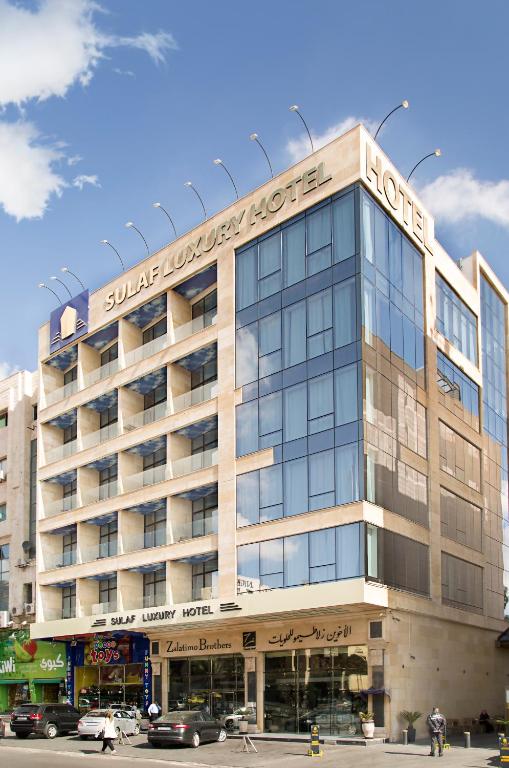 un gran edificio con un cartel encima en Sulaf Luxury Hotel, en Amán