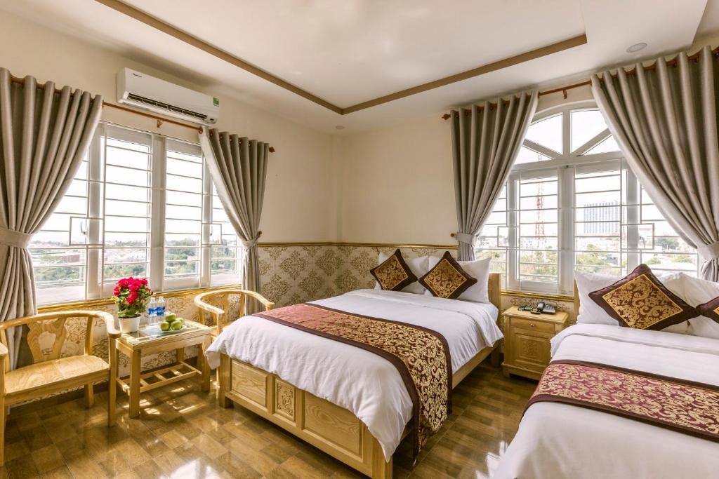 a hotel room with two beds and windows at AEC Hotel Ban Me in Buon Ma Thuot