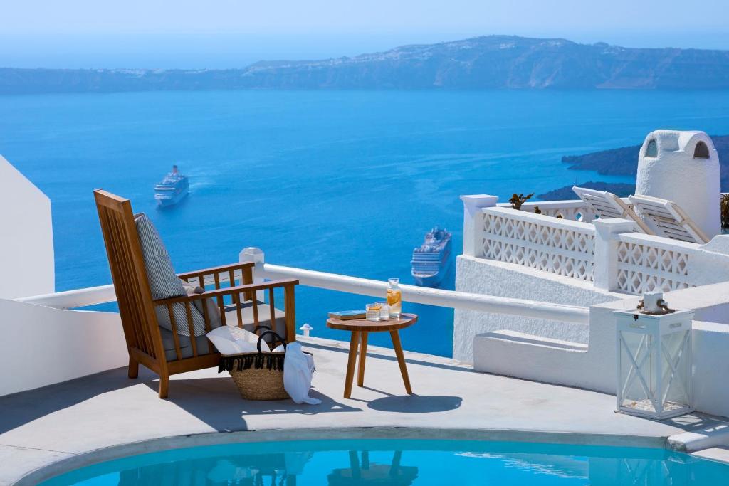 Habitación con balcón con vistas al océano, sillas y piscina. en Senses Boutique Hotel, en Imerovigli