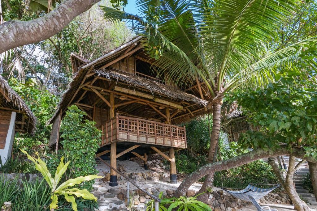 uma casa de bambu com uma palmeira em frente em Kookoo's nest eco-lodge em Siaton